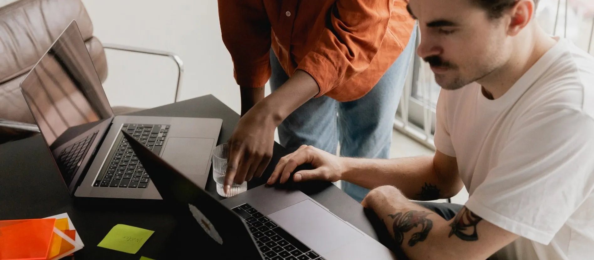 Twee collega's werken samen aan laptops op een bureau met kleurstalen en plakbriefjes